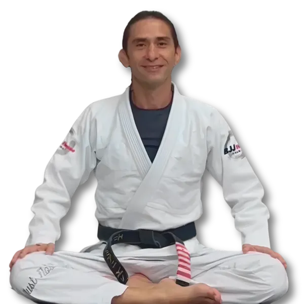 Helio Damiani Jr., seated on the mat in a white gi and black belt